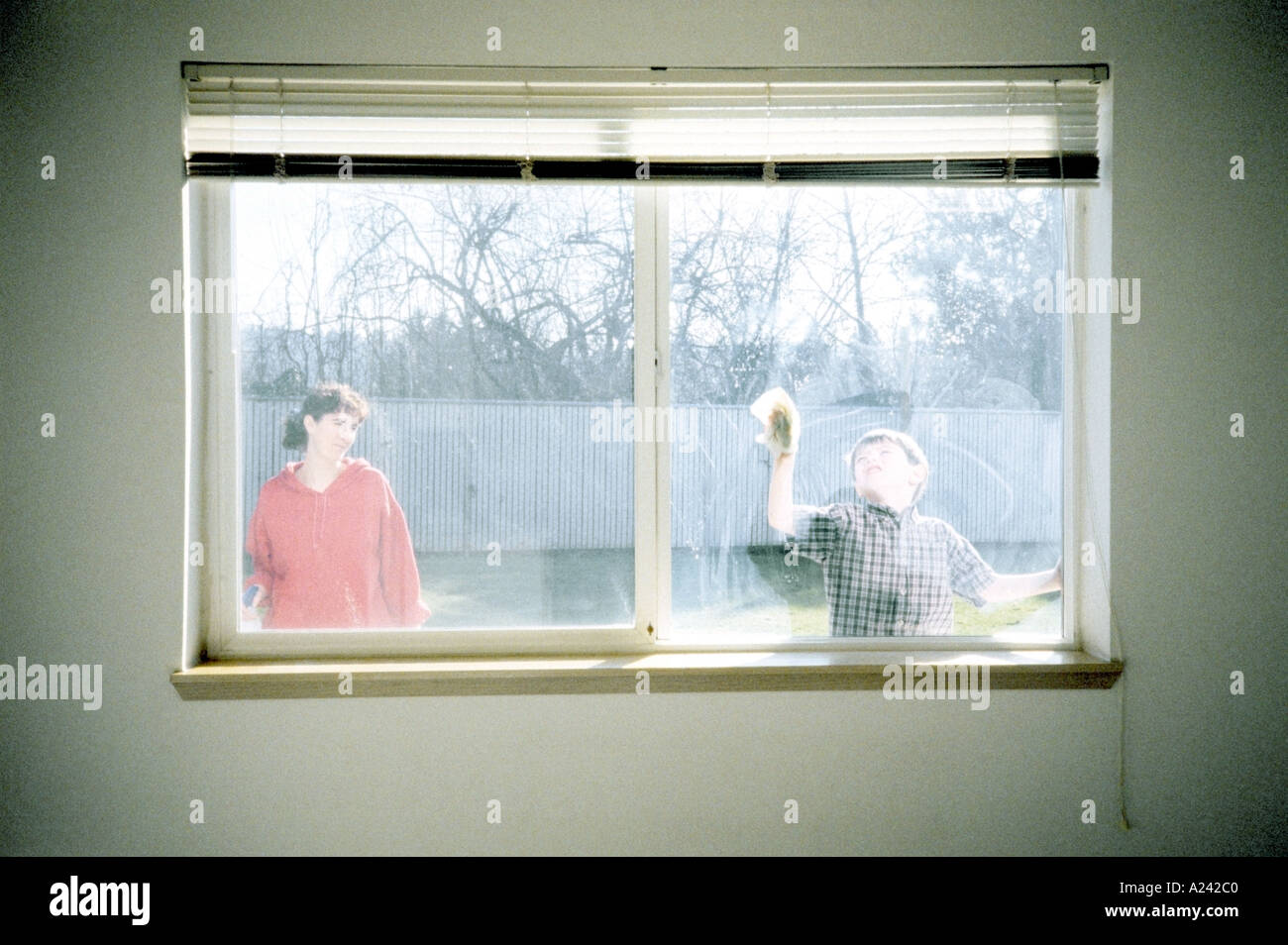 Mutter beobachtete Sohn waschen Fenster Aussicht vom Haus Stockfoto