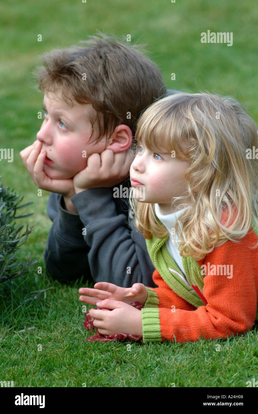 Jungen und Mädchen, die Verlegung auf dem Rasen, die gerade auf der Suche nachdenkliche Stimmung Stockfoto