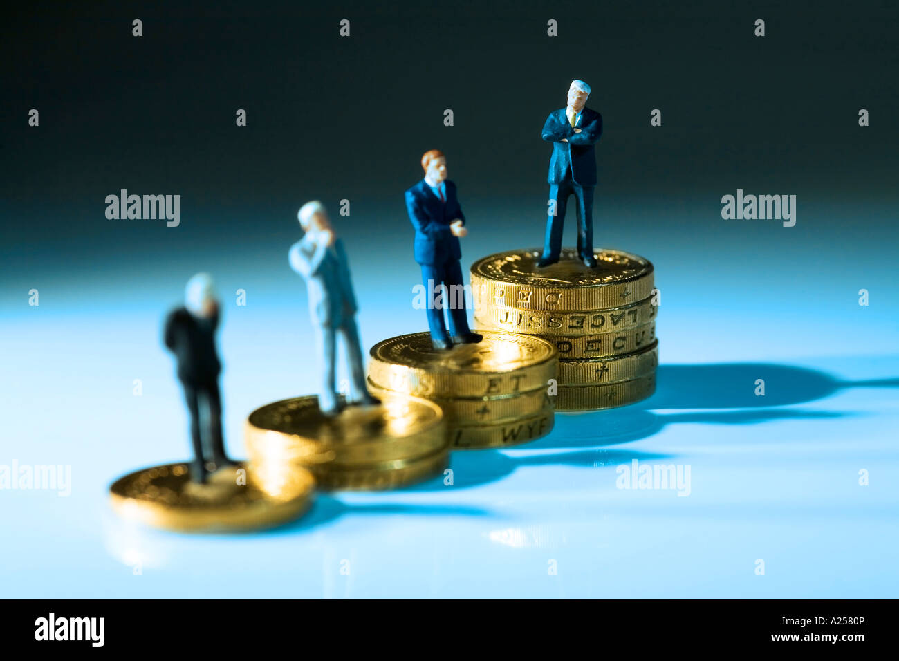 Miniatur-Geschäftsleute stehen auf Münzen. Dieses Foto zeigt die riesige Kluft bei den Löhnen in den Unternehmen Stockfoto
