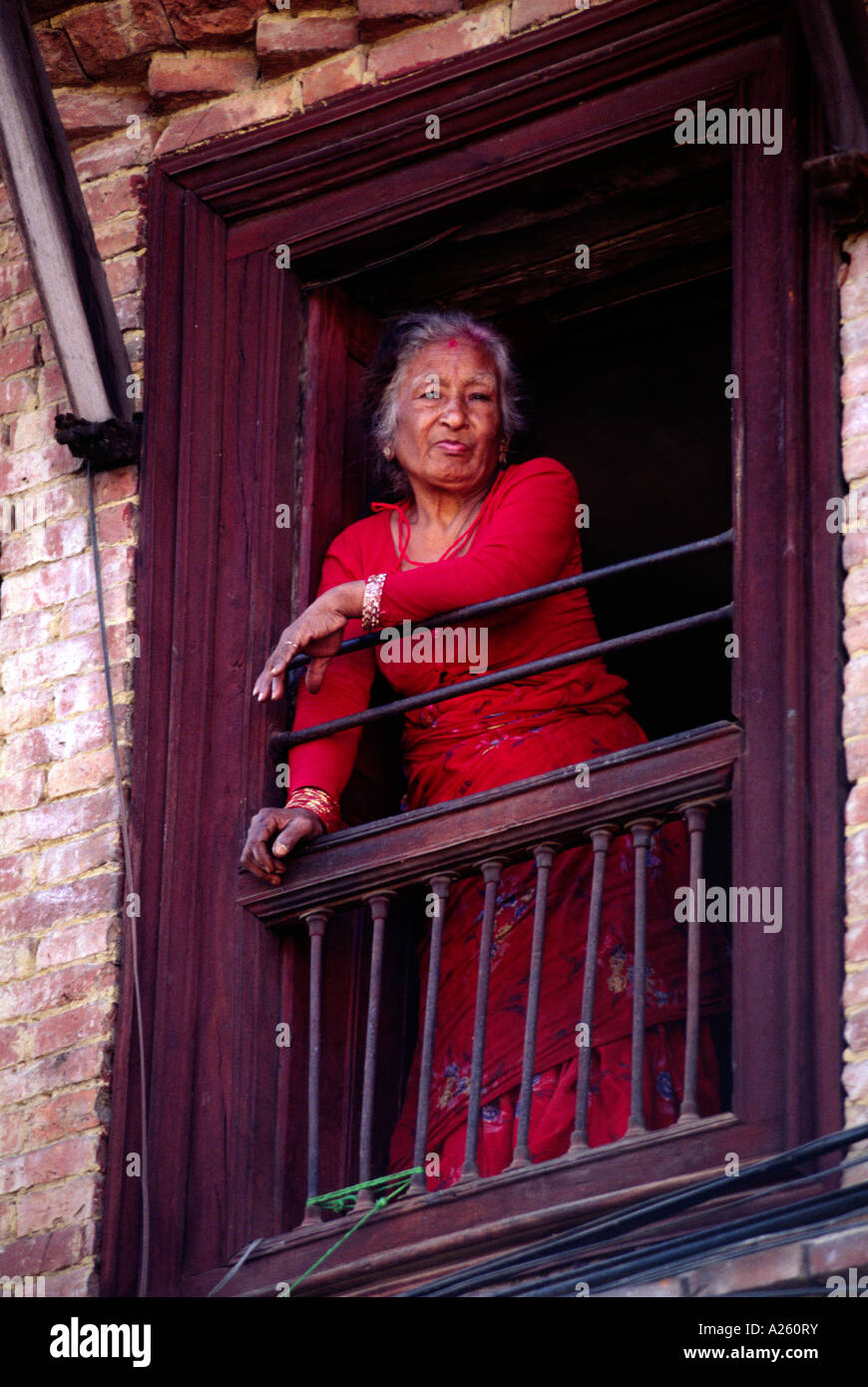 Eine NEPALESISCHE Frau schaut aus einem Fenster im oberen Stock BHAKTAPUR NEPAL Stockfoto