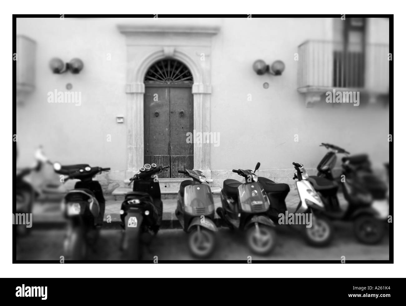 Motorroller geparkt vor einem Haus in Noto. Südliche Sizilien. Italien. B&W Foto Stockfoto