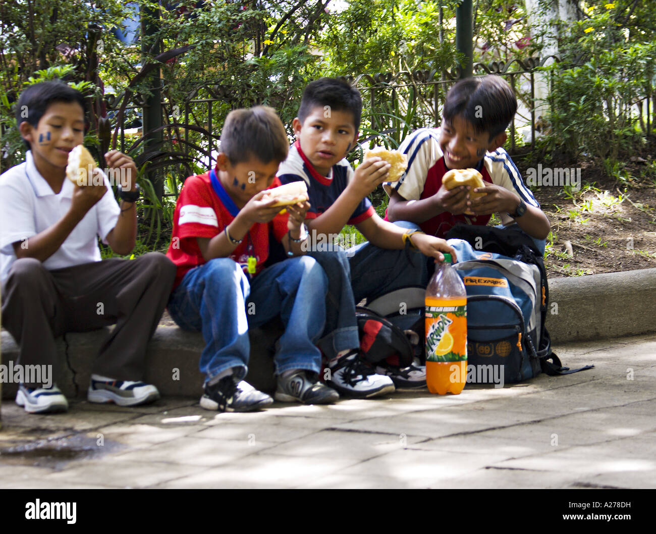 GUATEMALA ANTIGUA Guatemala Jungs Essen ihr Mittagessen auf einer Exkursion für Independence Day im Central Park von Antigua Stockfoto