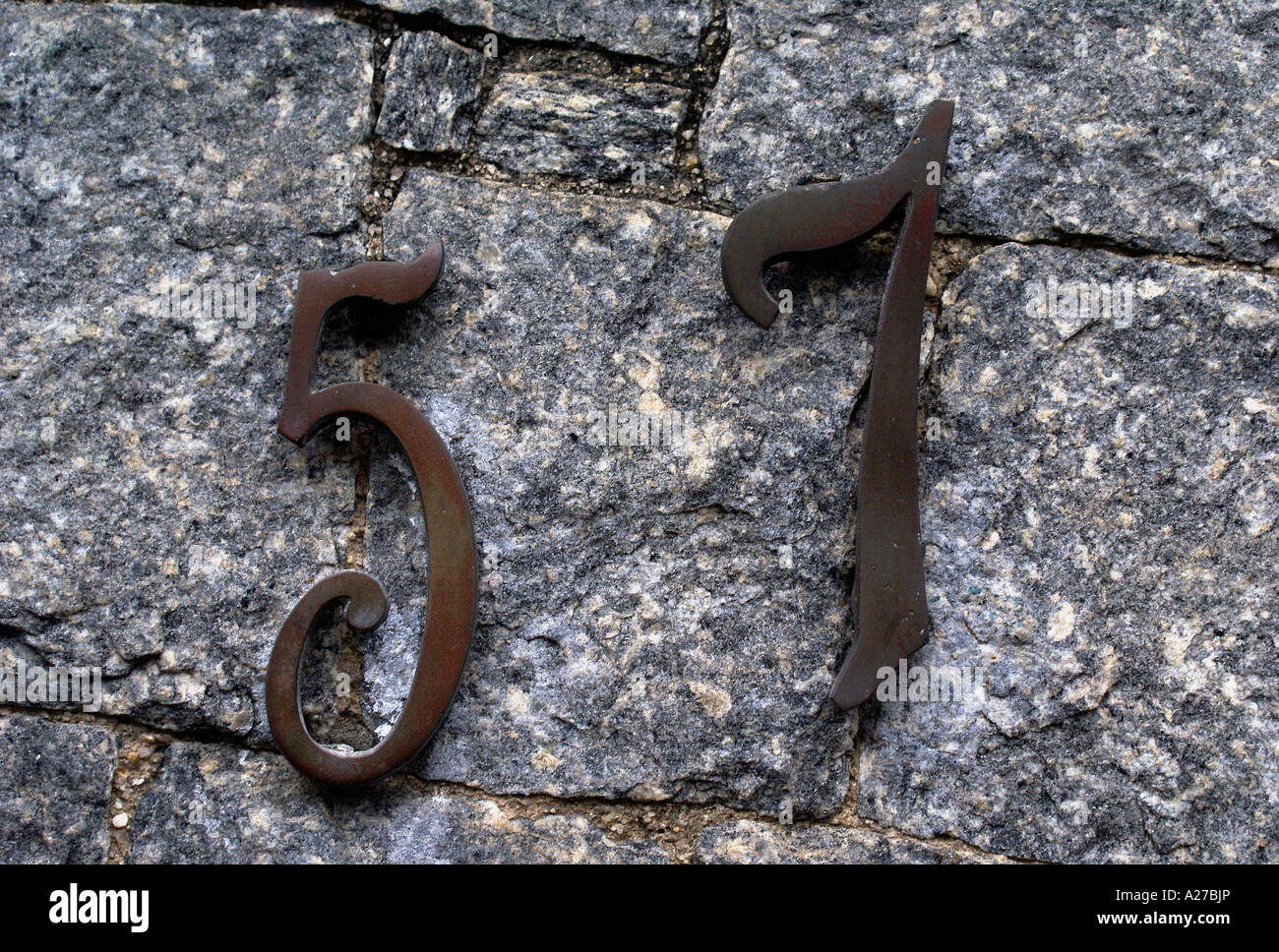 Hausnummer '57', Metall-Chiffre auf einer Steinmauer Stockfoto