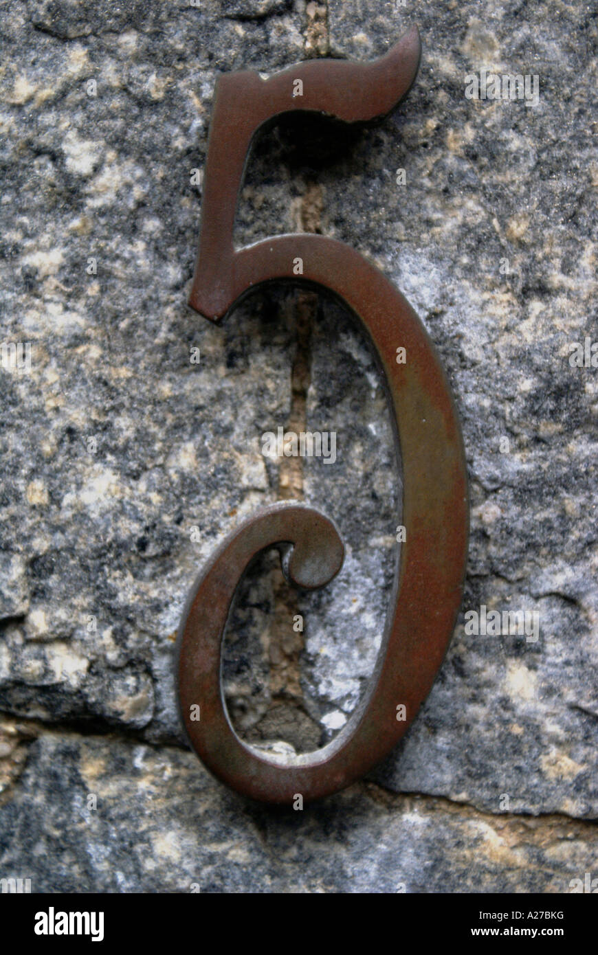 Hausnummer "5", Metall-Chiffre auf einer Steinmauer Stockfoto