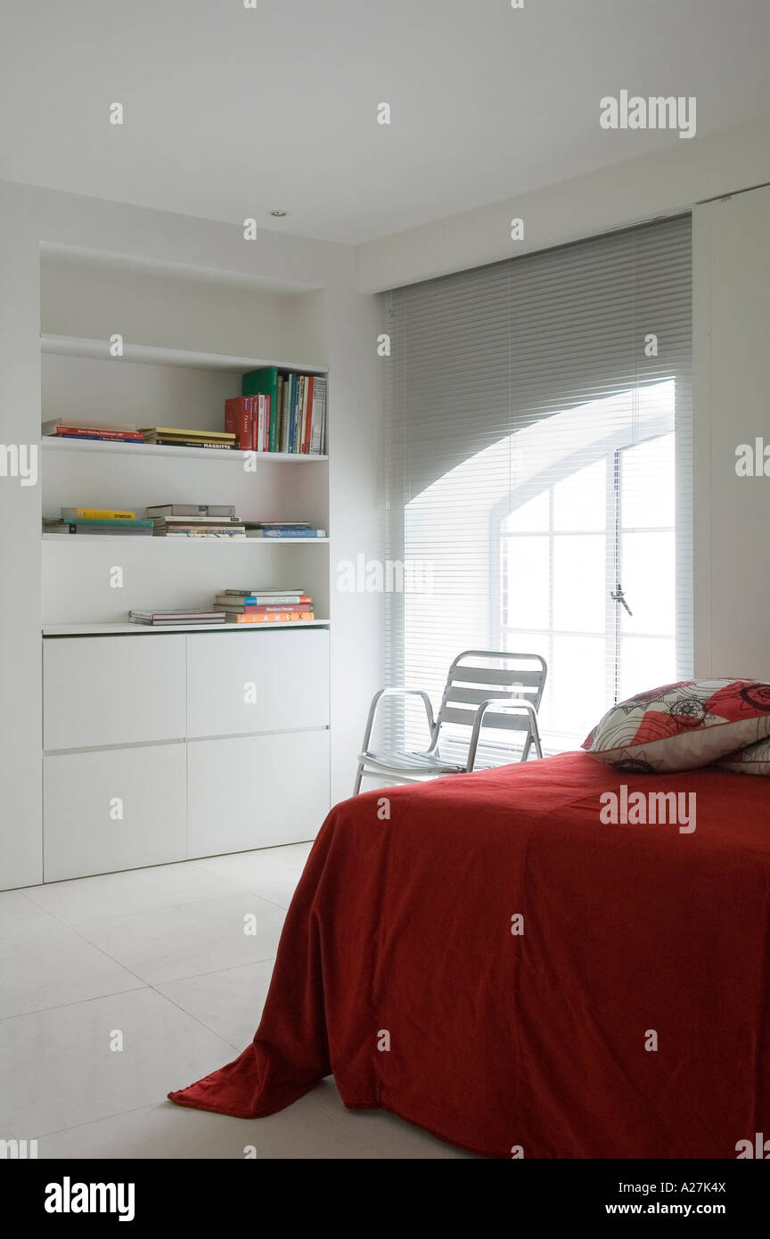 Ecke des Bettes mit rotem Einband und Regale in minimalistischen Lager Konvertierung Stockfoto