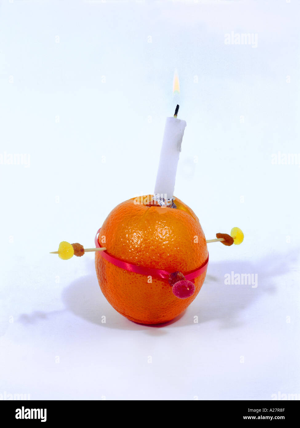 Christingle Orange symbolisiert die Welt, Kerze Jesus Christus das Licht der Welt, rotes Band das Blut Christi und die vier Süßigkeiten die vier Ecken Stockfoto