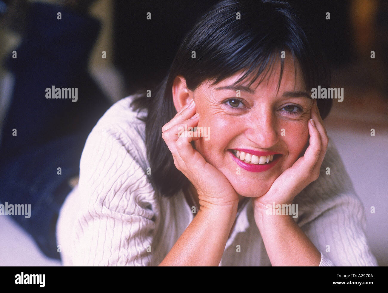 Dunkelhaarige Frau am Boden des Wohnzimmers mit Gesicht schalenförmig in Händen L Frost Stockfoto