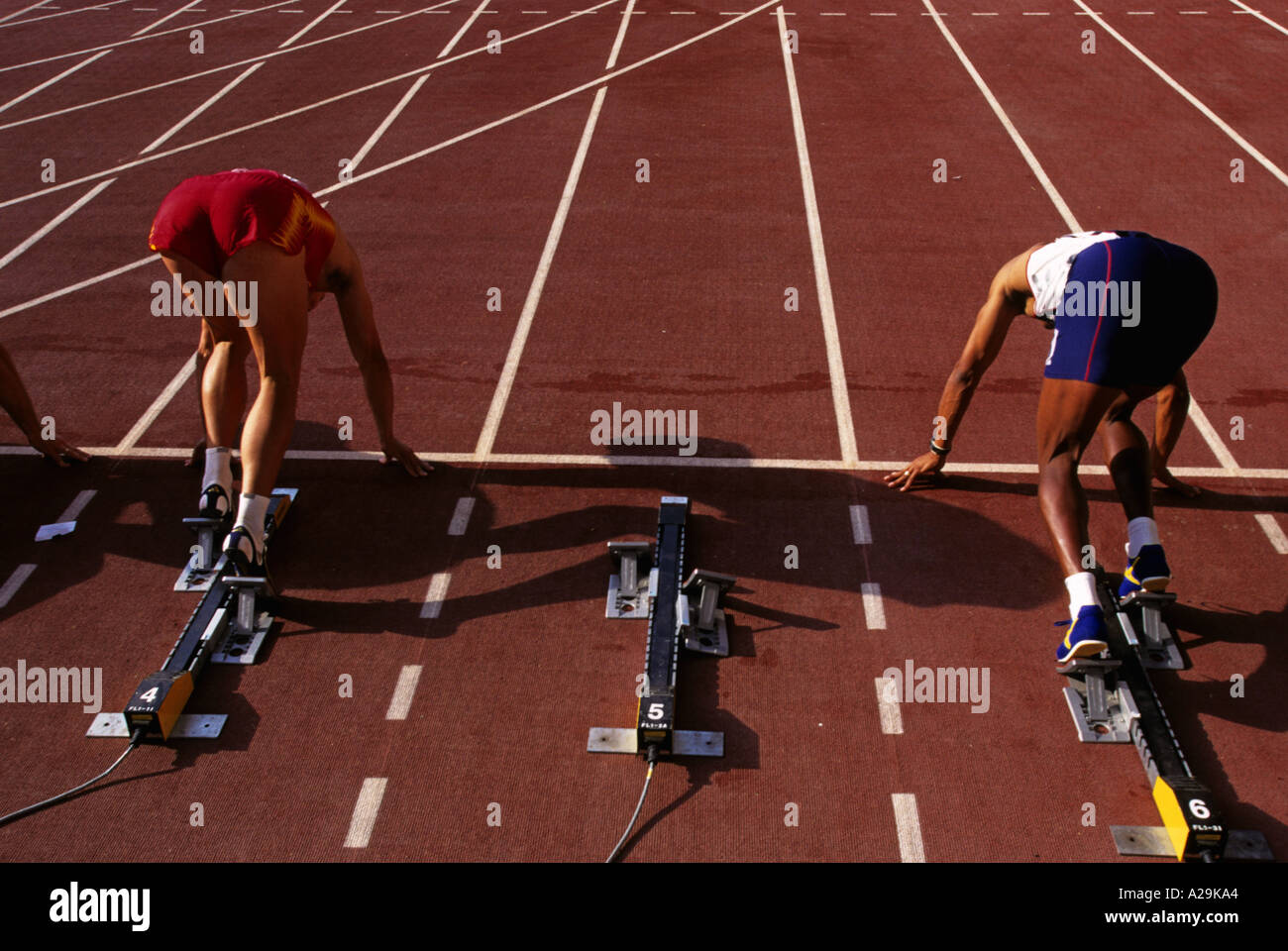 Ansicht von hinten zwei männliche Athleten in ihre Blockaden auf dem Weg zum Jahresbeginn eine Sprint-Rennen Stockfoto