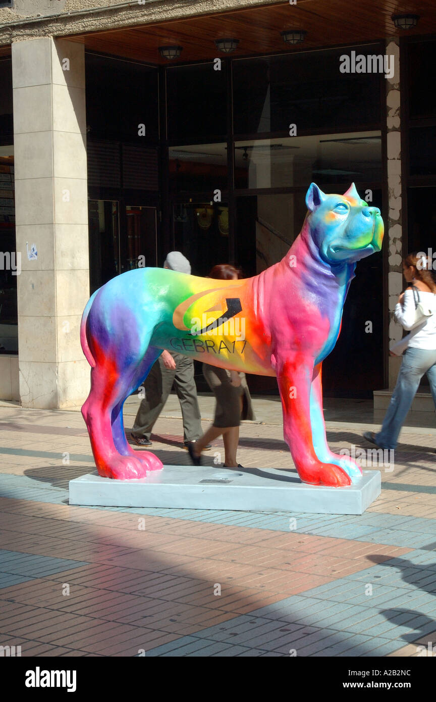 Eine mehrfarbige Kanarischen Hund Skulptur mit Passanten im Hintergrund, Las Palmas de Gran Canaria, Gran Canaria, Kanarische Inseln Stockfoto