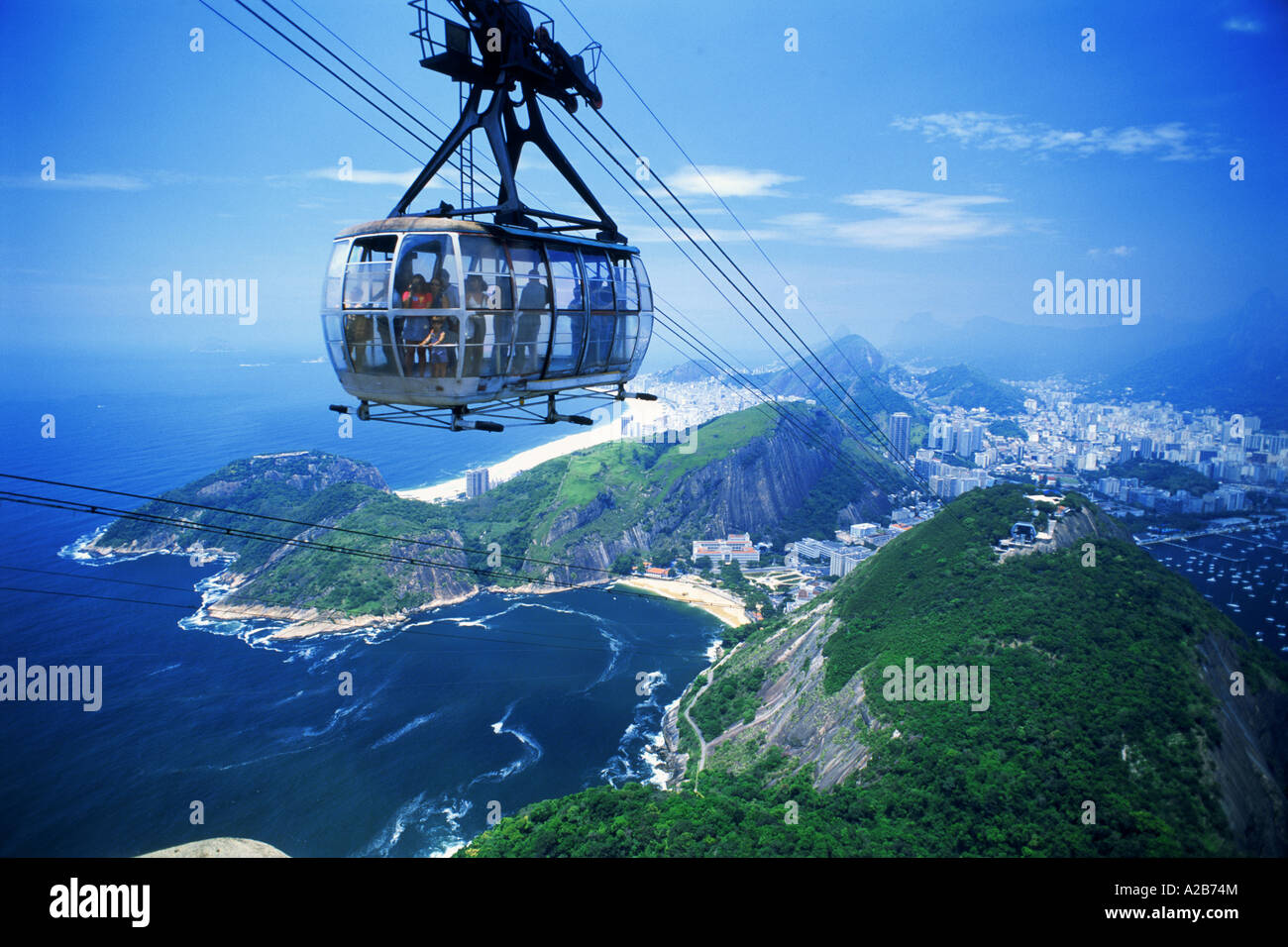 Seilbahn mit Passagieren, die kurz vor der Spitze der Zuckerhut oder Pao de Acucar mit Küstenlinien von Rio De Janeiro unten geladen Stockfoto