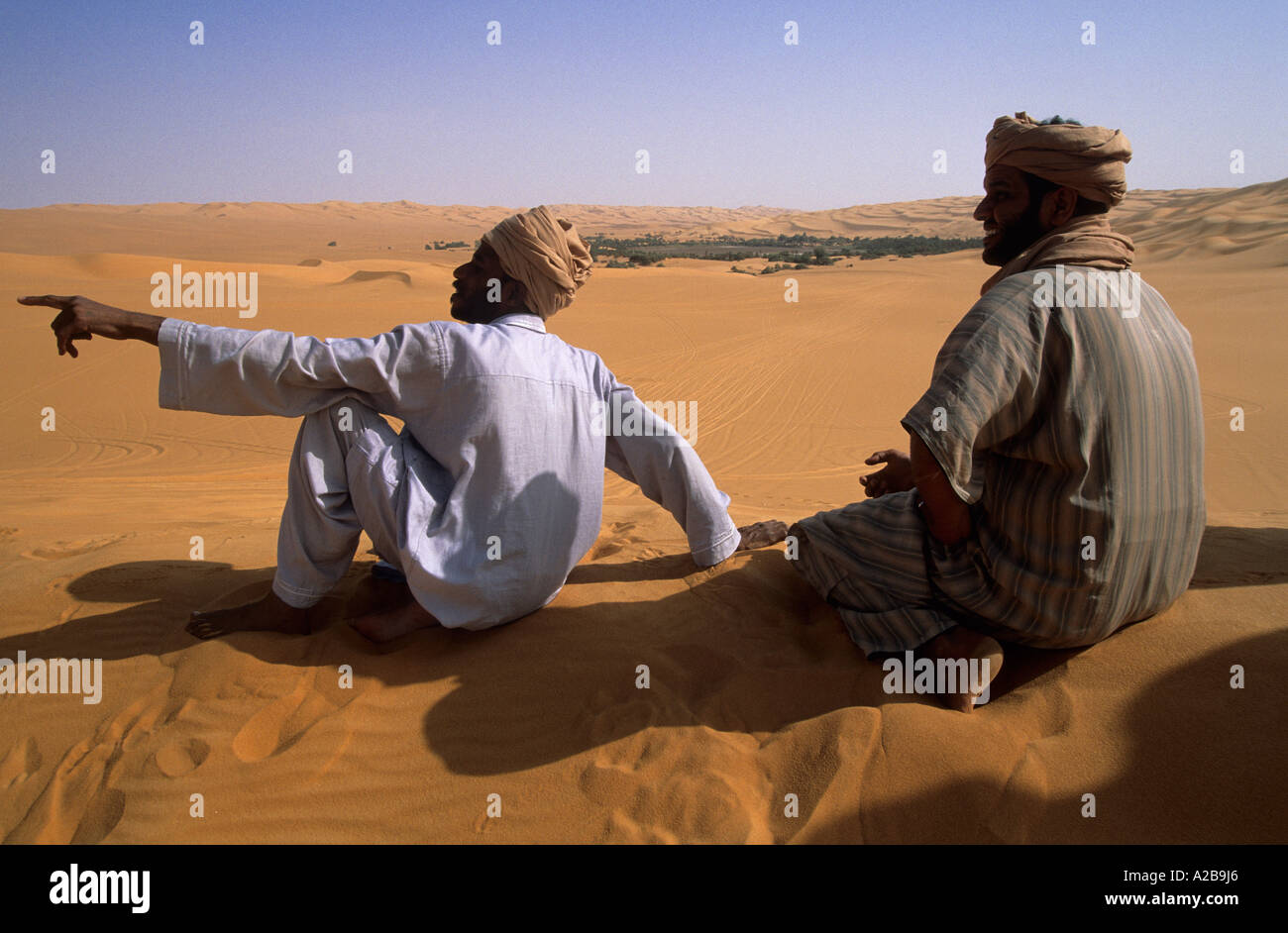 Zwei Männer in traditionellen Kleidern sitzen auf einer Düne, Libyen Stockfoto