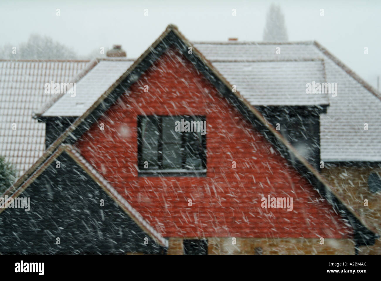 Dachformen und Giebelenden werden bei einem Schneesturm im späten Frühling, Essex England UK, zwei Mal näher am Haus mit Fenster und kleinerem Giebel über der Garage geschlossen Stockfoto