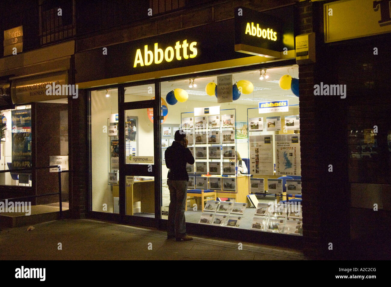 Frau mit Blick auf Häuser für Verkauf durch das Fenster eines Makler-Büros in der Stadt von Stowmarket Suffolk UK Dezember 2006 Stockfoto