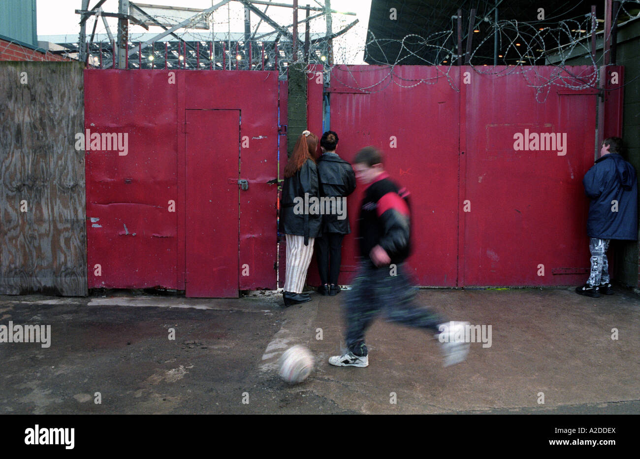 Kinder auf der Suche durch die verschlossenen Tore am Fußballplatz Prenton Park während eines Spiels. Stockfoto