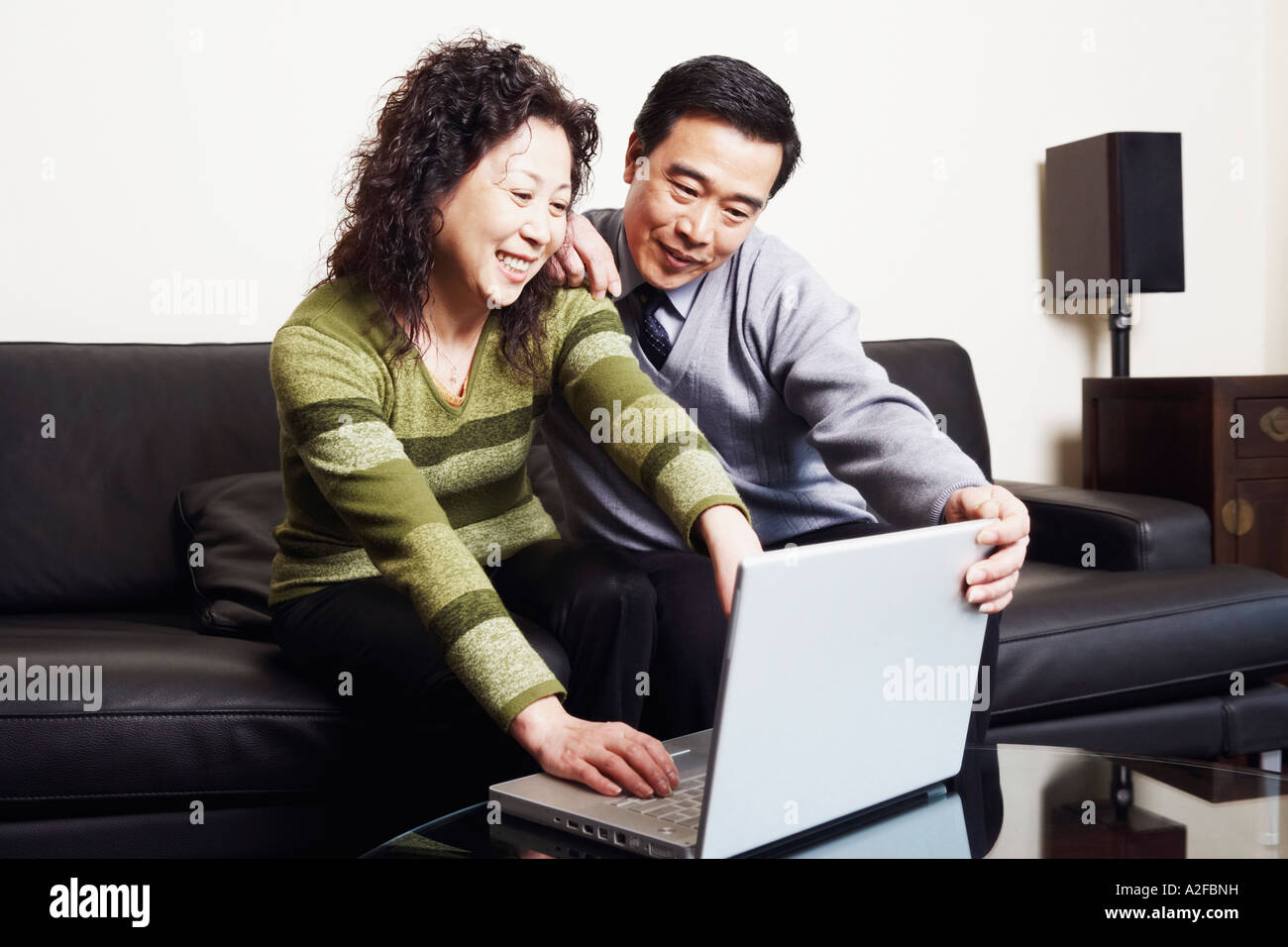 Älteres Paar sitzt auf einer Couch mit einem laptop Stockfoto