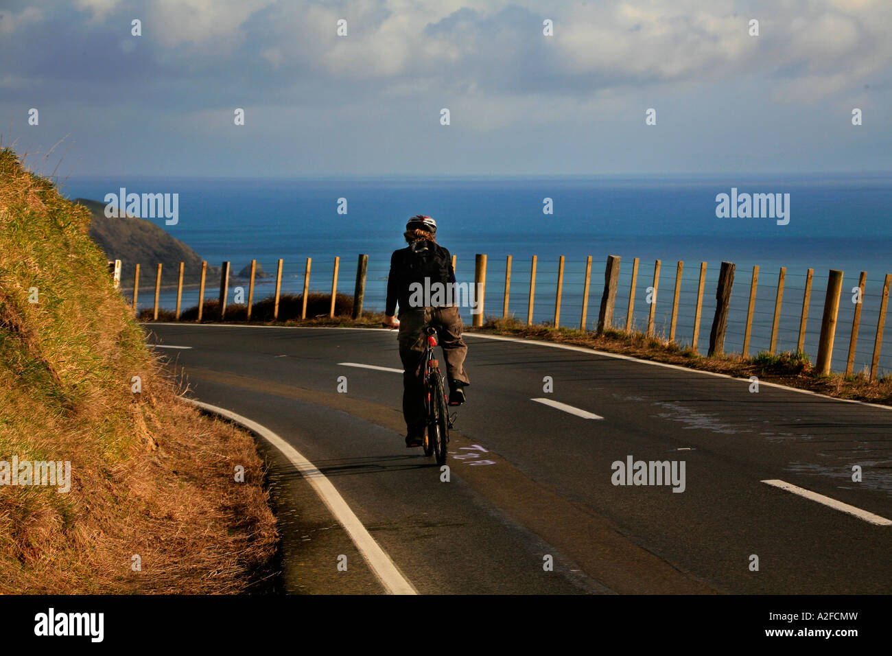 Ein einsamer Radfahrer auf kurvigen Straße Landschaft in der Nähe von Paekakariki Wellington New Zealand Stockfoto