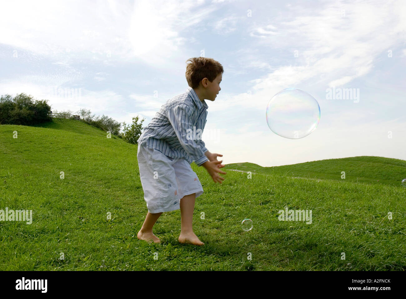 Jungen (4-7) spielt mit Seifenblasen, Seitenansicht Stockfoto