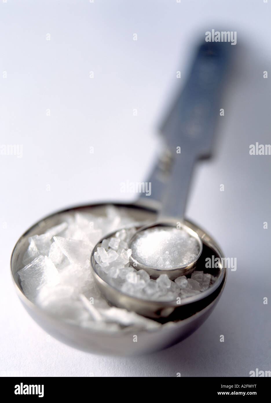 Messlöffel mit drei verschiedenen Arten von Salz auf weißem Hintergrund Stockfoto