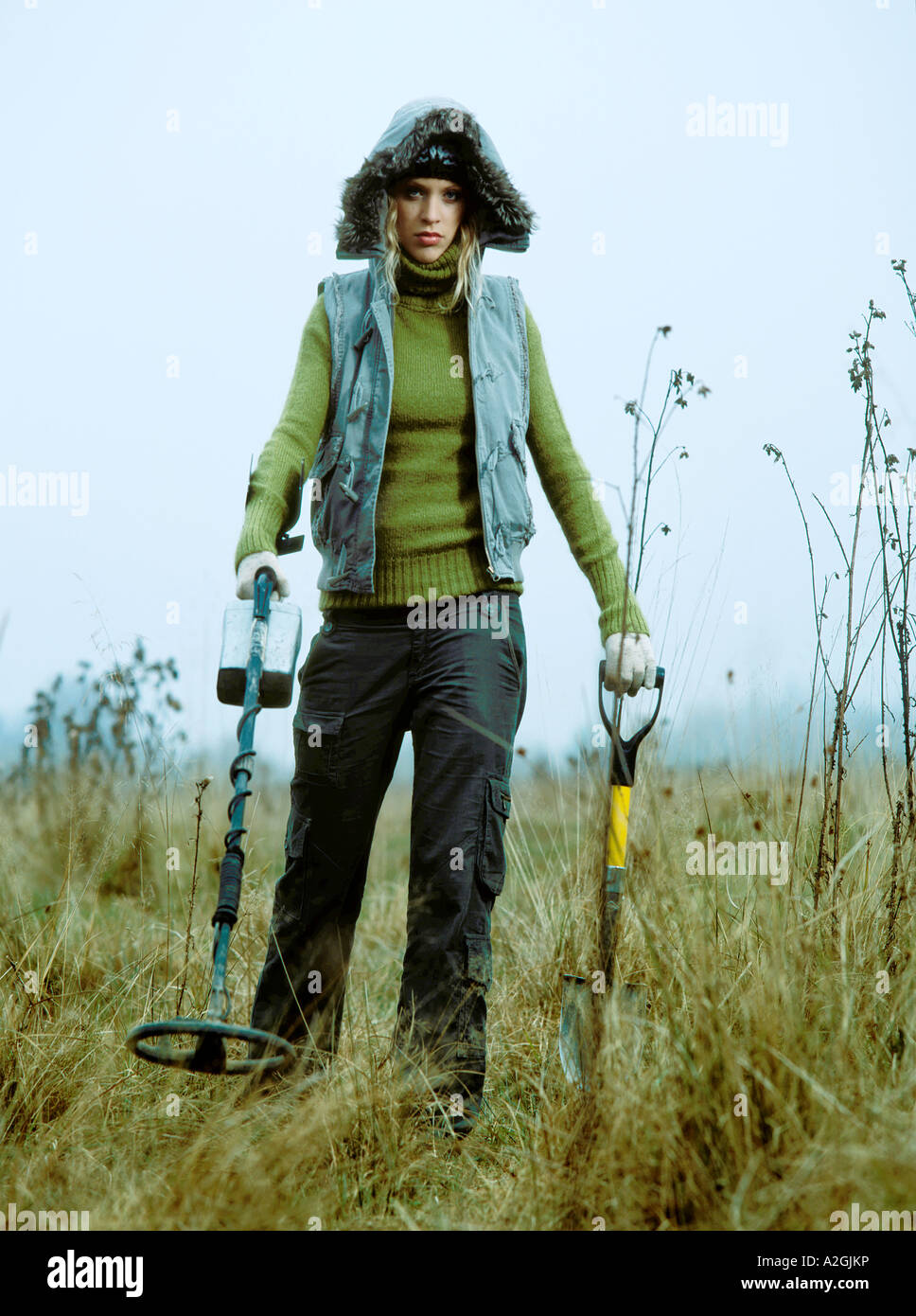 1212968 Outdoor-Tag im Herbst Frau junge 25 30 blonde Wiese Feld Rasen Stand aussehen Weste blau Handschuh Handschuhe weiß golf Stockfoto