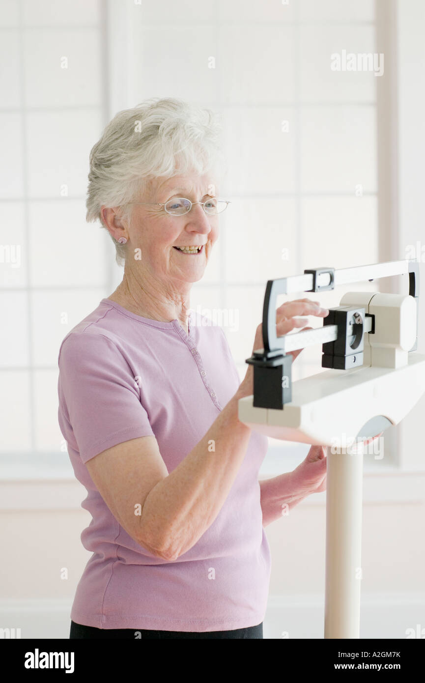 Ältere Frau mit einem Gewicht von selbst im Maßstab Stockfoto