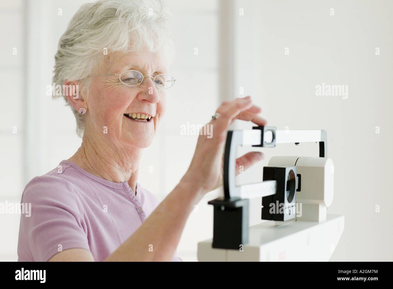 Ältere Frau mit einem Gewicht von selbst im Maßstab Stockfoto