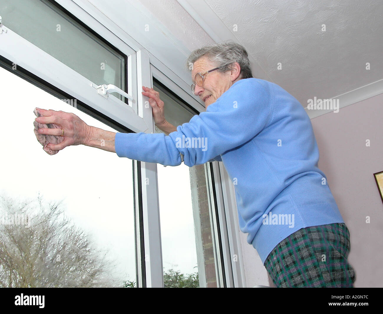 ältere Frau auf eine Leiter, die Reinigung der Fenster in ihrem Haus Stockfoto
