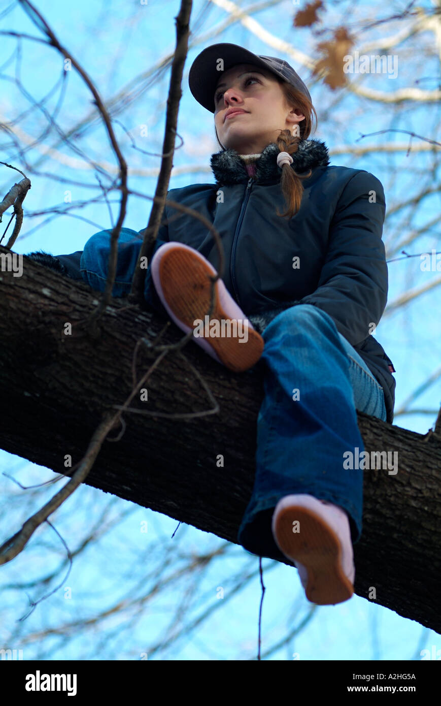 Junge Frau saß in einem Baum Stockfoto