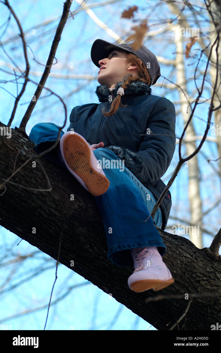 Junge Frau saß in einem Baum Stockfoto