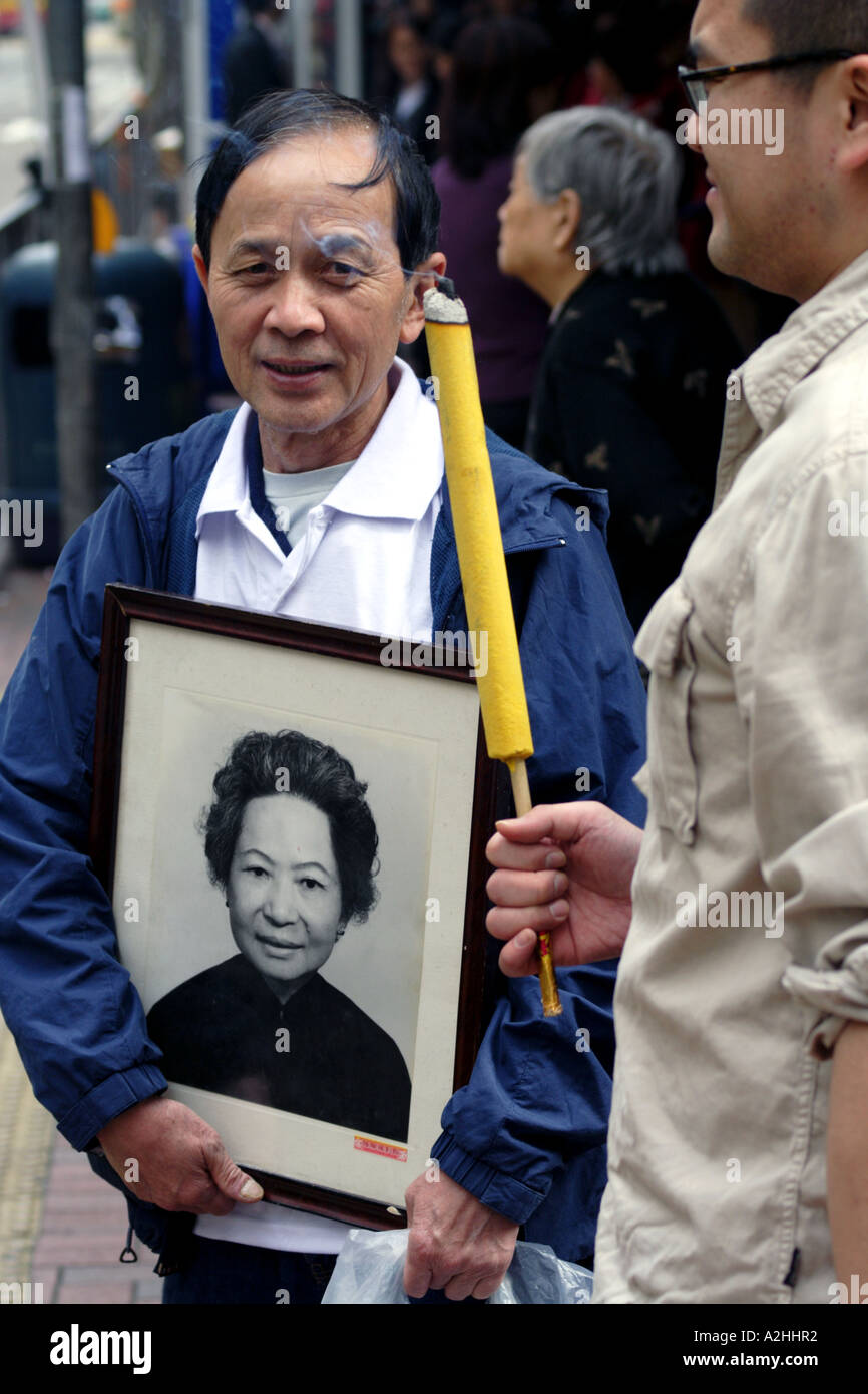 Mann und erwachsener Sohn mit Foto von seiner verstorbenen Mutter, auf seinem Weg nach Zahlen Hinsicht, Hong Kong, China Stockfoto