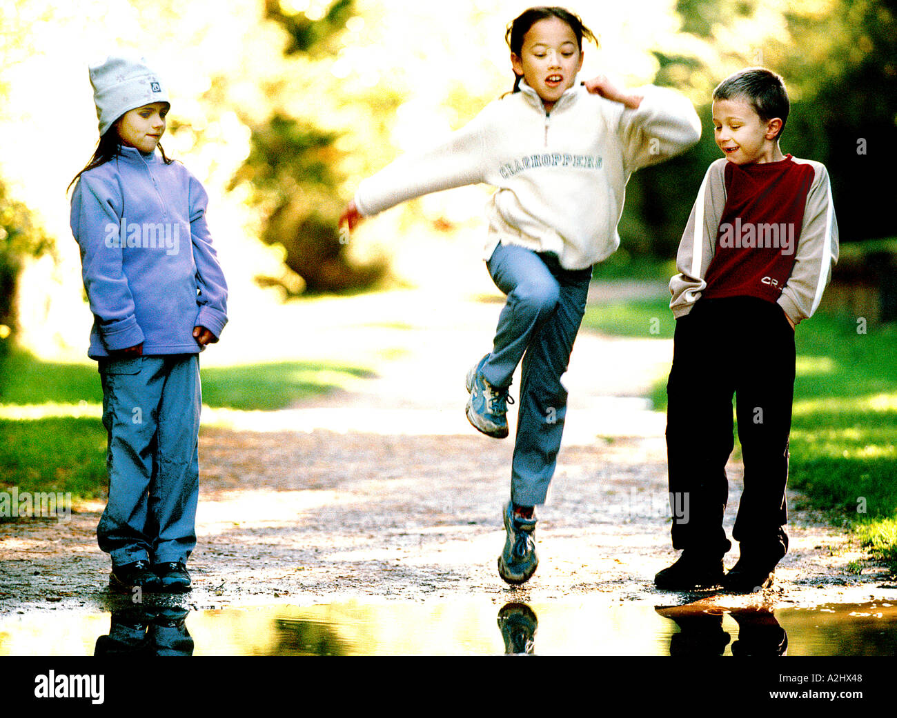 3 Kinder im Alter von 6-8 spielen in einem Park, 2 Mädchen und 1 ist ein Junge. Stockfoto