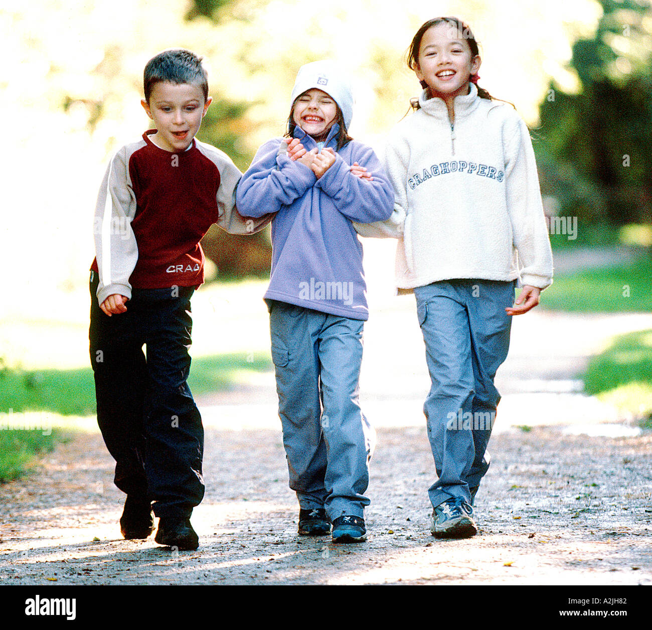 Drei Kinder Wandern in den Wäldern tragen legere Kleidung Wandern und Spaß haben. Es ist Alter 6-8, gibt es 2 Mädchen und 1 junge Stockfoto