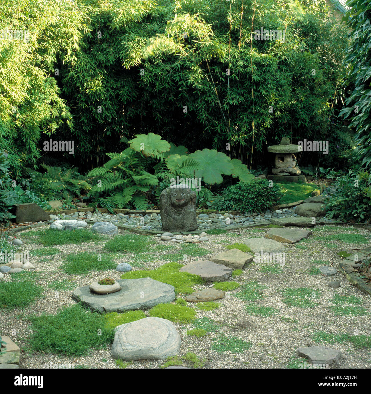 Orientalischer Garten mit natürlichen Pflastersteinen und Skulptur unter arundinaria Stockfoto