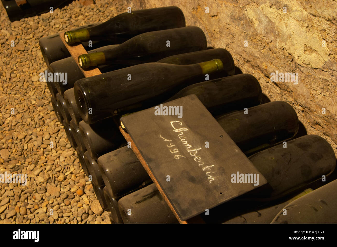 Im unterirdischen Weinkeller: ein Haufen von Flaschen von Chambertin Grand Cru 1996 rot Burgund Wein mit der Appellation in weißer Schrift auf eine schwarze Kreidetafel an Bord auf einem steinigen Kiesböden, Maison Louis Jadot, Beaune Côte d ' Cote d oder Bourgogne Burgund Burgund Frankreich Französisch Europa Europäische geschrieben Stockfoto