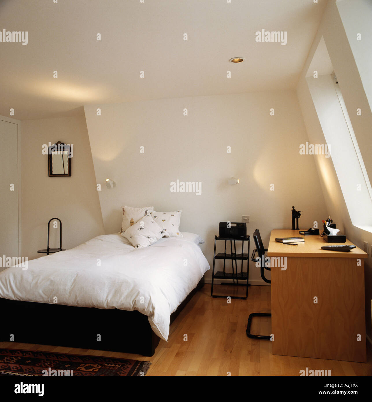 Moderne weiße Dachgeschoss Schlafzimmer mit Schreibtisch und Holzboden ...