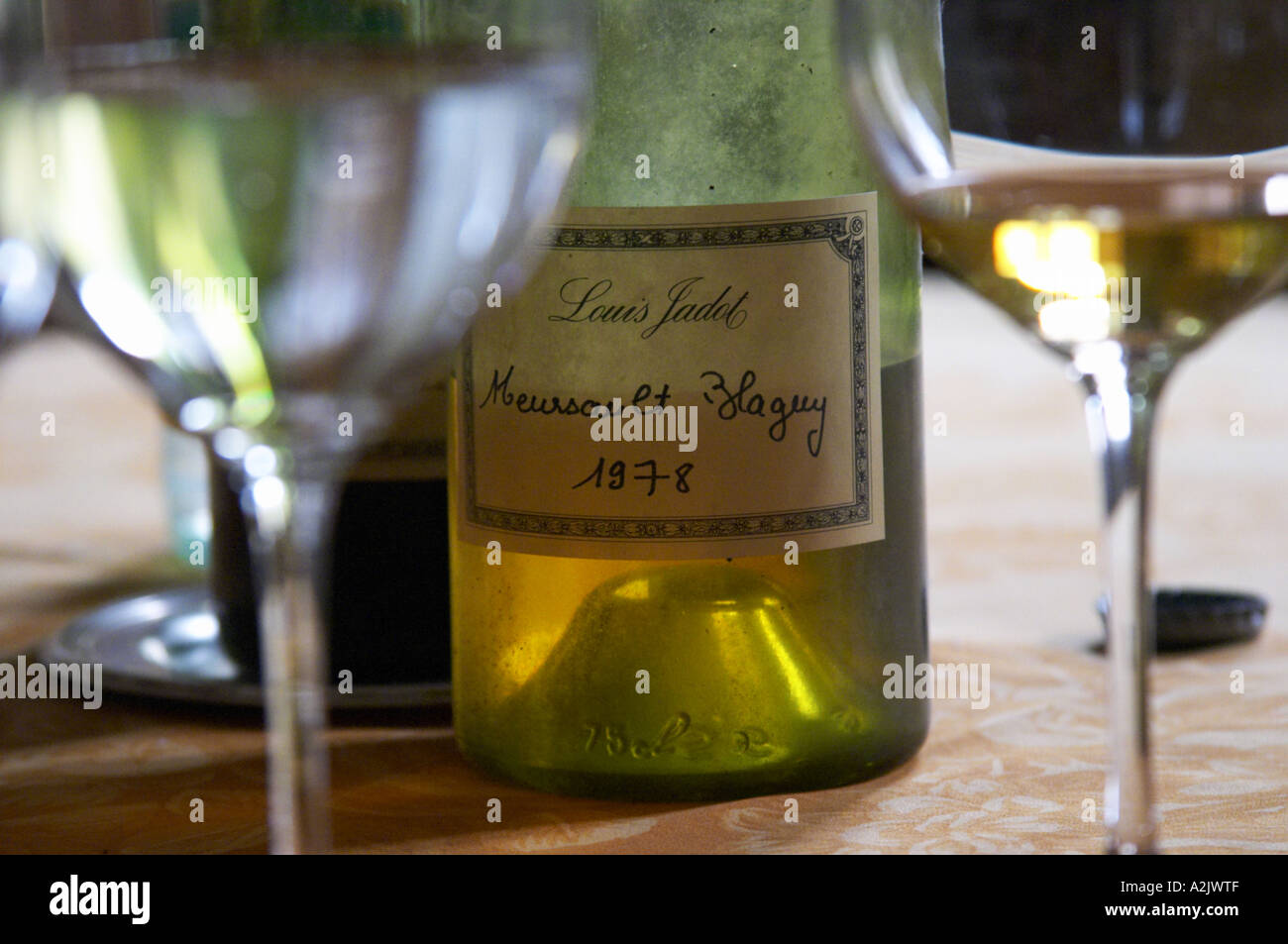 Ein halb leeren staubige alte Flasche mit einem handgeschriebenen Etikett Louis Jadot Meursault Blagny 1978 Weißburgunder und zwei Gläser Stockfoto