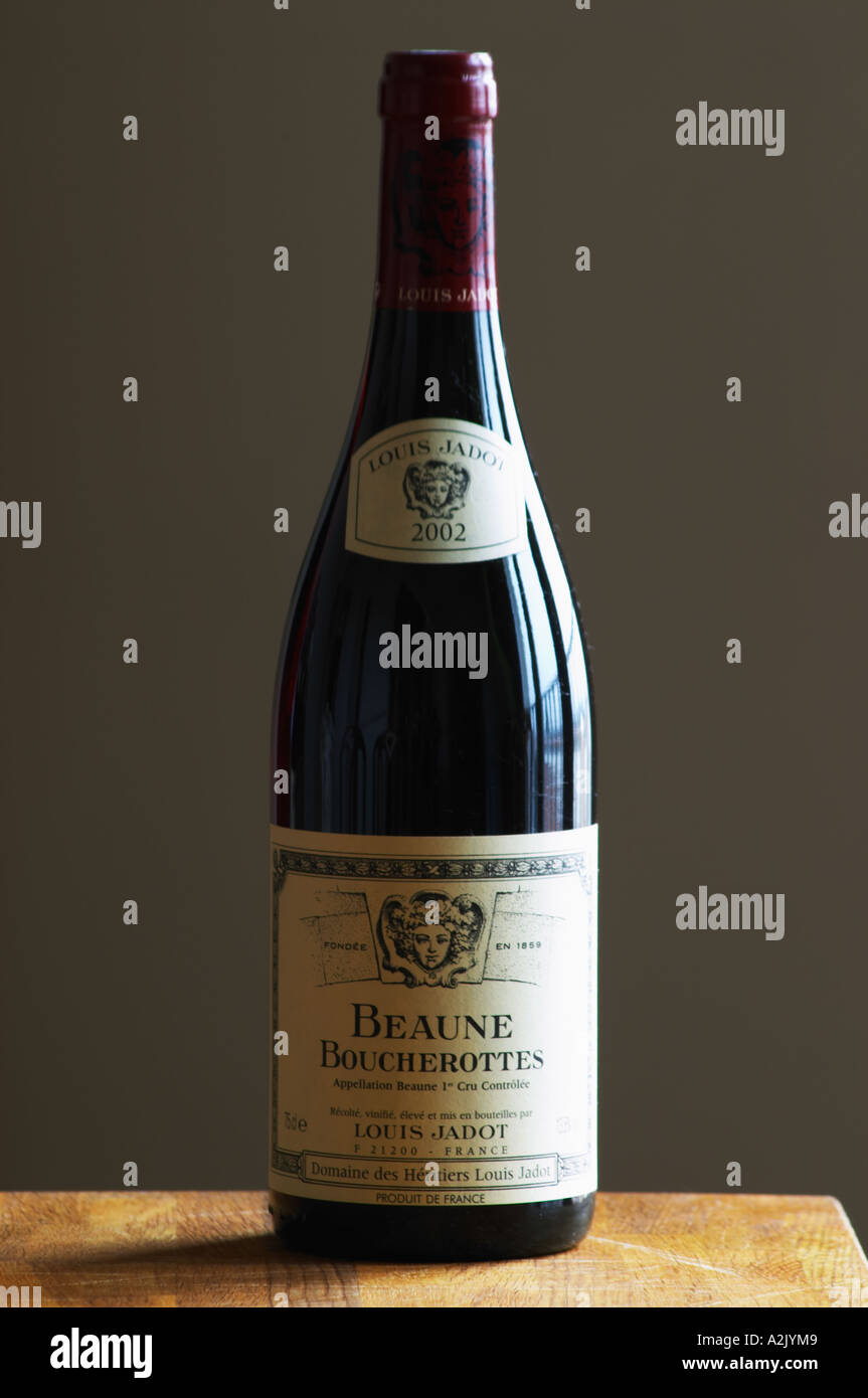 Eine Flasche Maison Louis Jadot Bourgogne Beaune Boucherottes Premier 1er Cru 2002 roten Burgunder Wein steht auf einer hölzernen Tischplatte. Hintergrundbeleuchtung Hintergrundbeleuchtung Hintergrundbeleuchtung beleuchtet. grau hinterlegte Sidelit Streiflicht, Maison Louis Jadot, Beaune Côte d ' Cote d oder Bourgogne Burgund Burgund Frankreich Französisch Europa Europäische grau Stockfoto