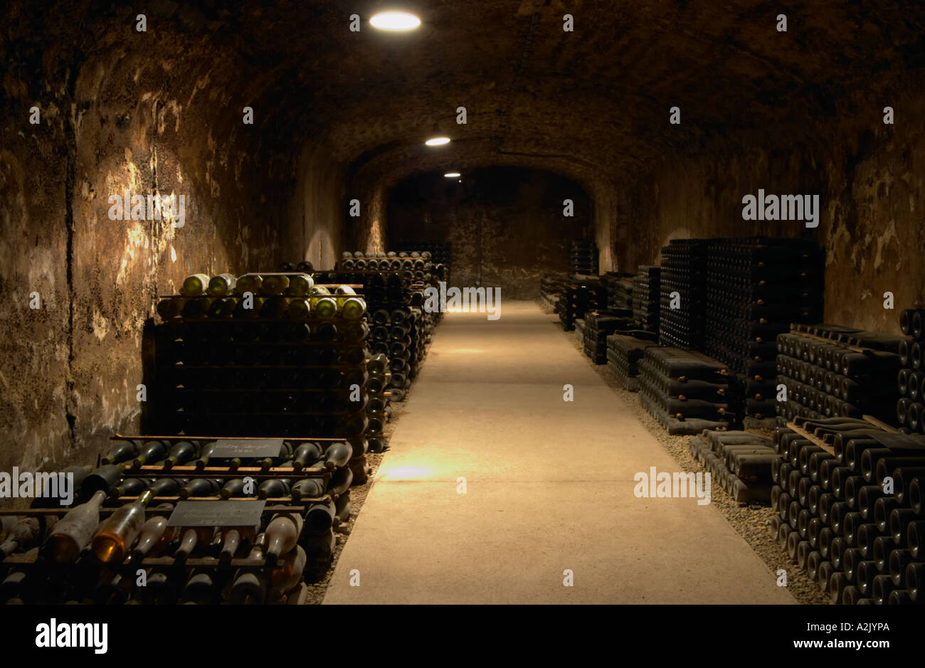 Im unterirdischen Weinkeller: haufenweise Tausende von Flaschen Burgund Wein auf einer steinigen Kiesböden gewölbten Gewölbedecke mit kontrastierenden Lichter, Maison Louis Jadot, Beaune Côte d ' Cote d oder Bourgogne Burgund Burgund Frankreich Französisch Europa Europäische Stockfoto