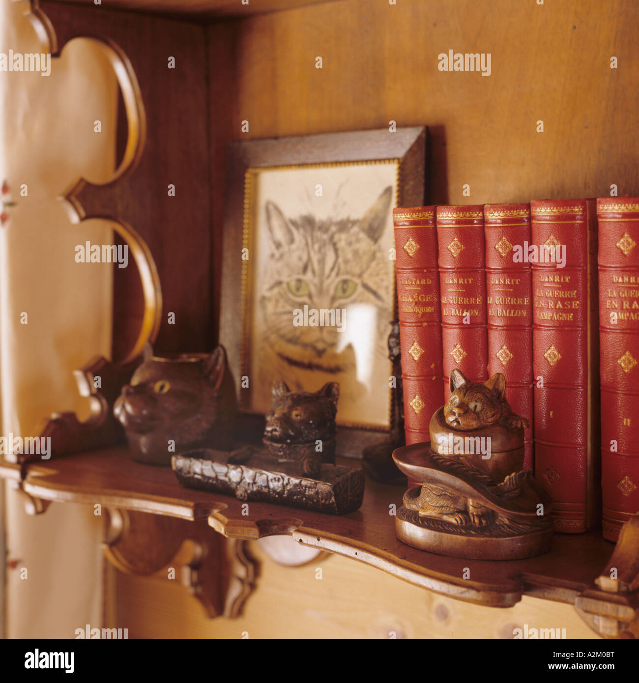 Bücher und Katze Ornamente auf einem geschnitzten hölzernen Regal Stockfoto