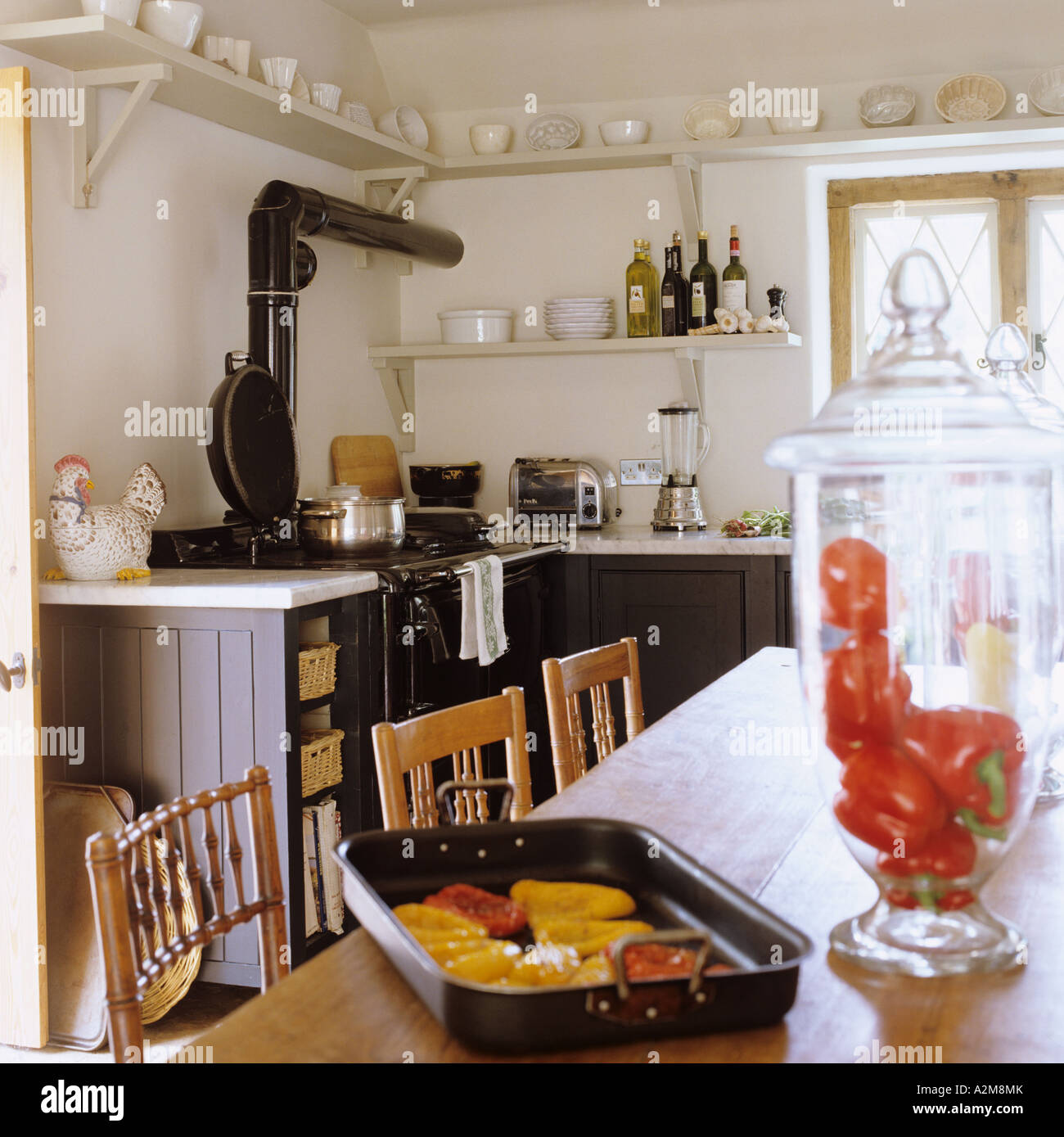Küche mit Aga und Paprika im Vordergrund auf Holztisch Stockfoto