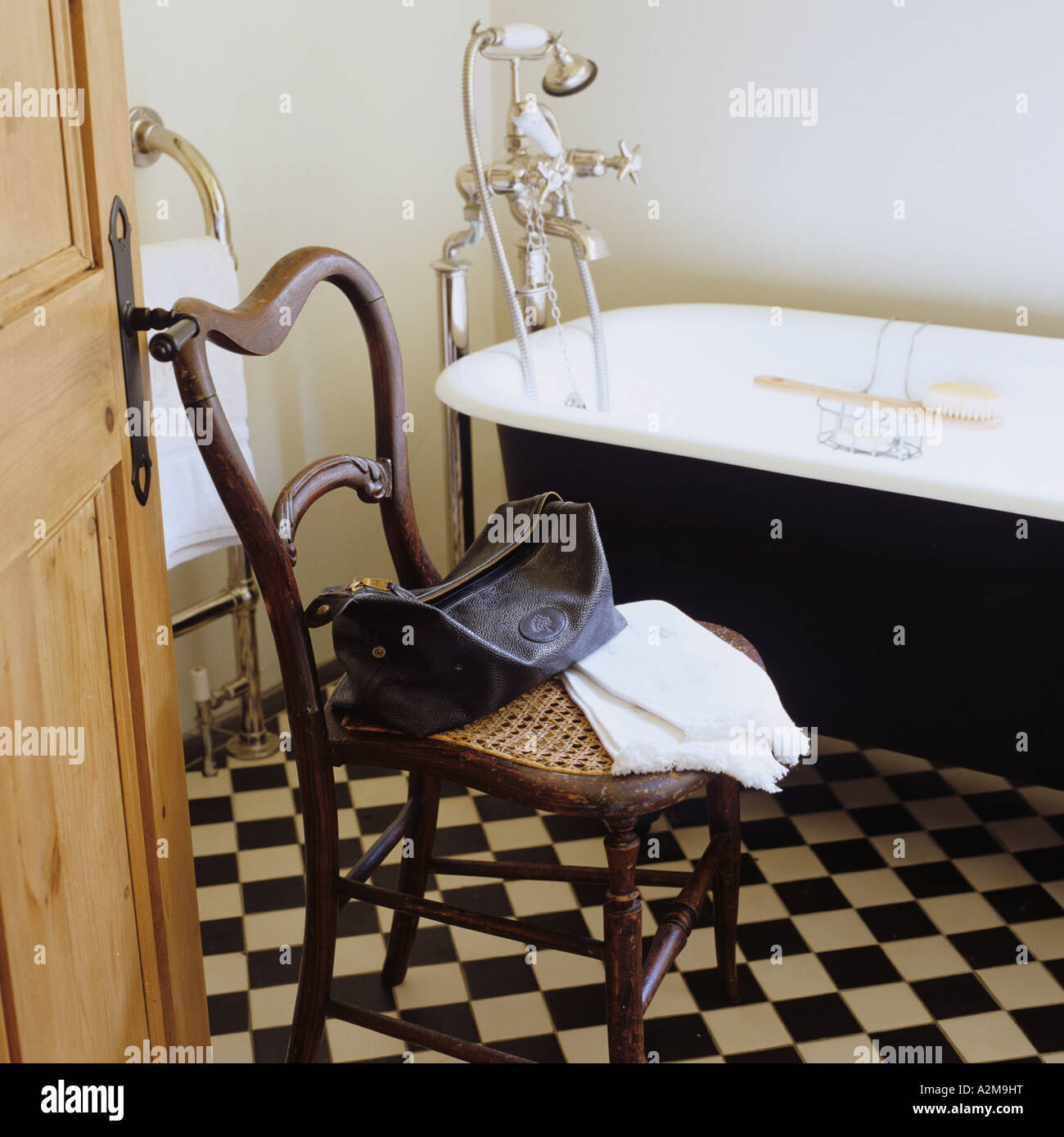 Waschzeug und Handtuch auf Stuhl im Bad mit karierten Bodenfliesen Stockfoto