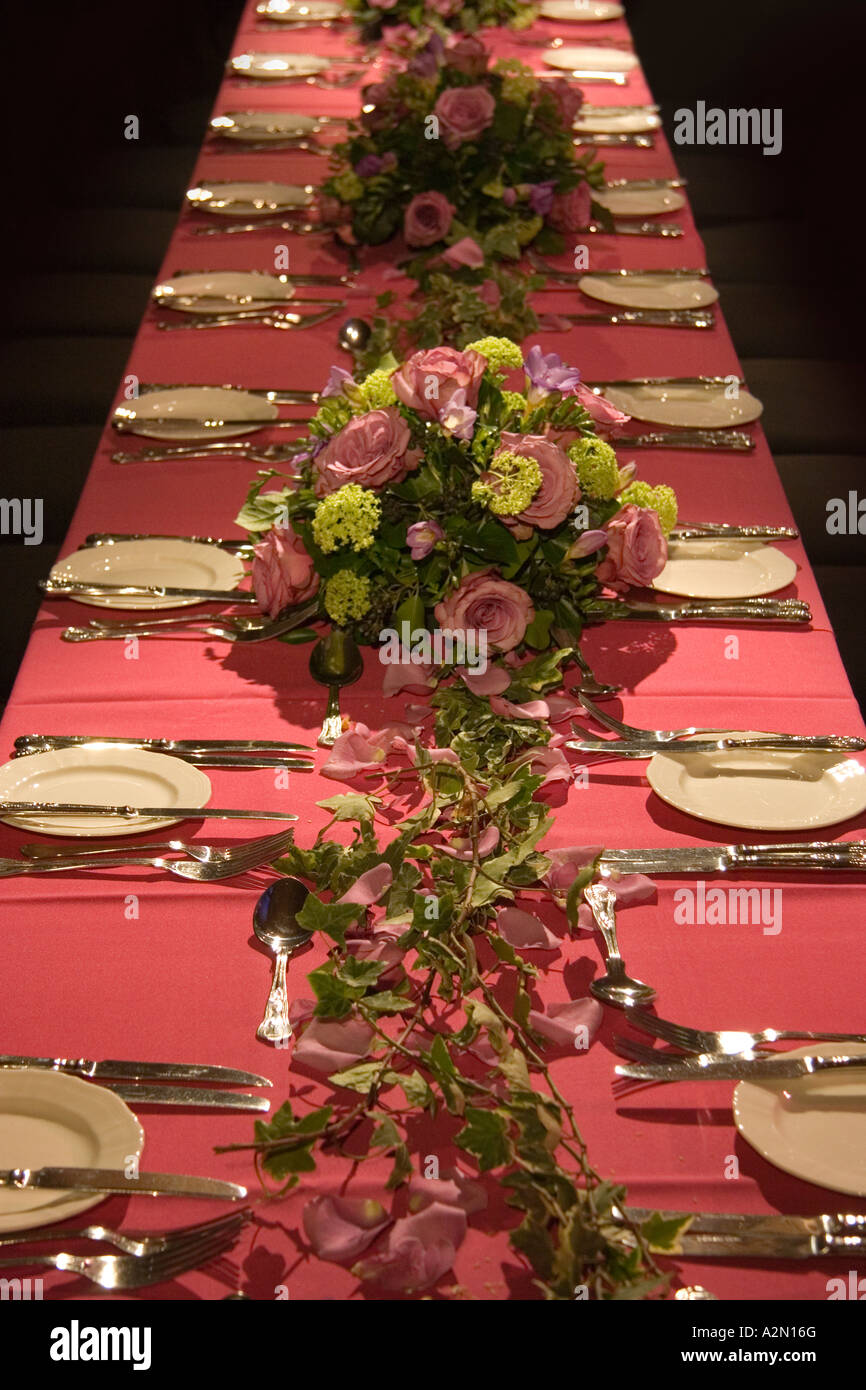 Ein langer Tisch mit Abendessen Einstellungen und bunten Blumen-arrangements Stockfoto