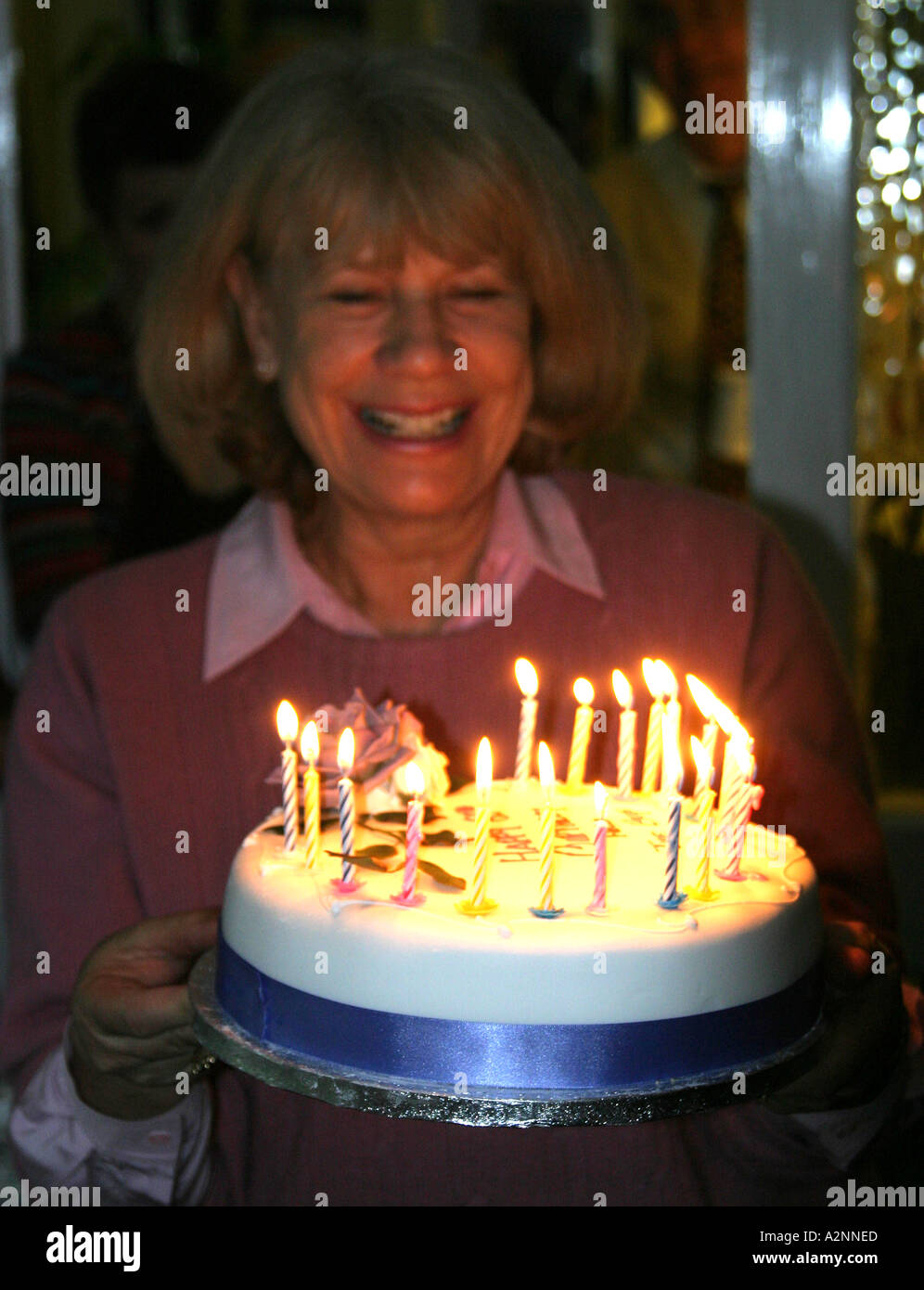 Geburtstagskind hält 60. Geburtstagskuchen mit brennenden Kerzen Stockfoto