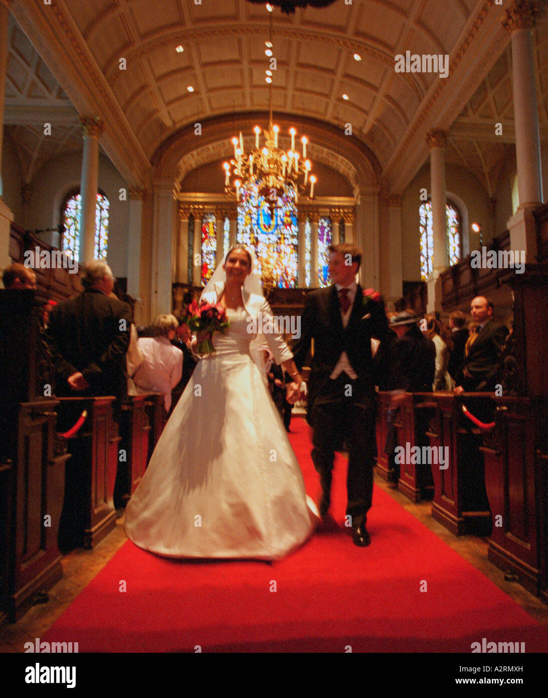 Braut mit ihrem Bräutigam zu Fuß durch den Mittelgang des Str. Georges Kirche London nach ihrer Trauung Stockfoto