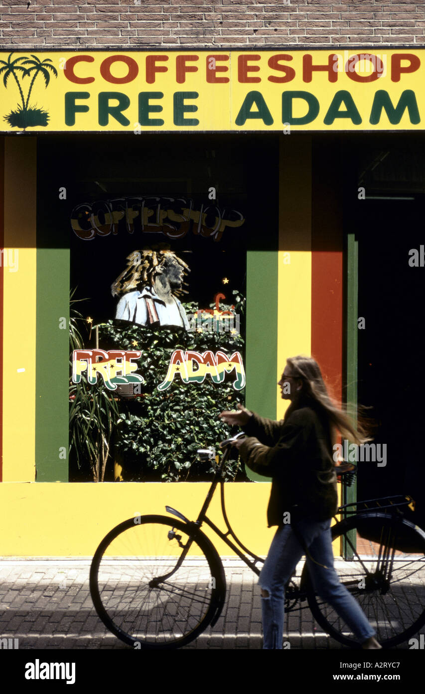 junge Frau schieben ihr Fahrrad vorbei an einem Coffeeshop in amsterdam Stockfoto