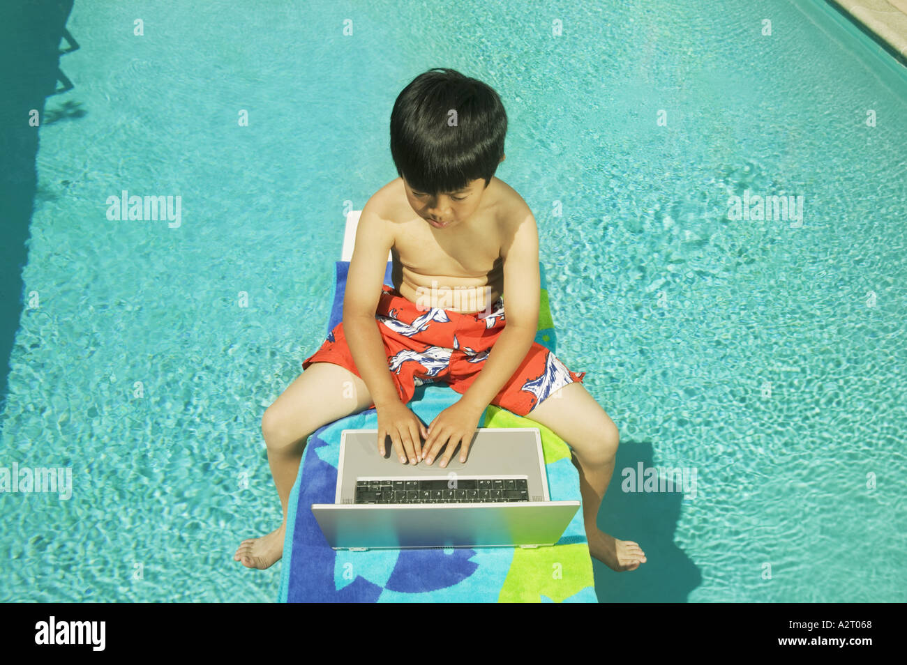 Youngster arbeiten auf seinem Laptop am Pool Stockfoto