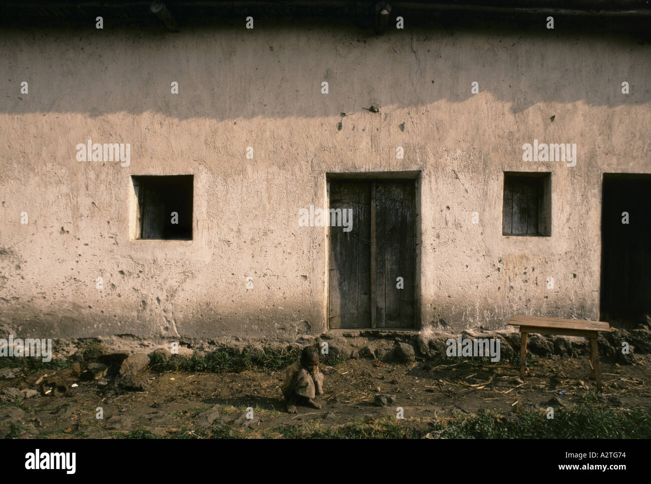ruandische Flüchtlinge Juli 1994 Heimkehr Flüchtlinge Kind kauerte in der fötalen Position allein neben verlassenen Haus in leere Dorf in der Nähe von ruhengeri Stockfoto