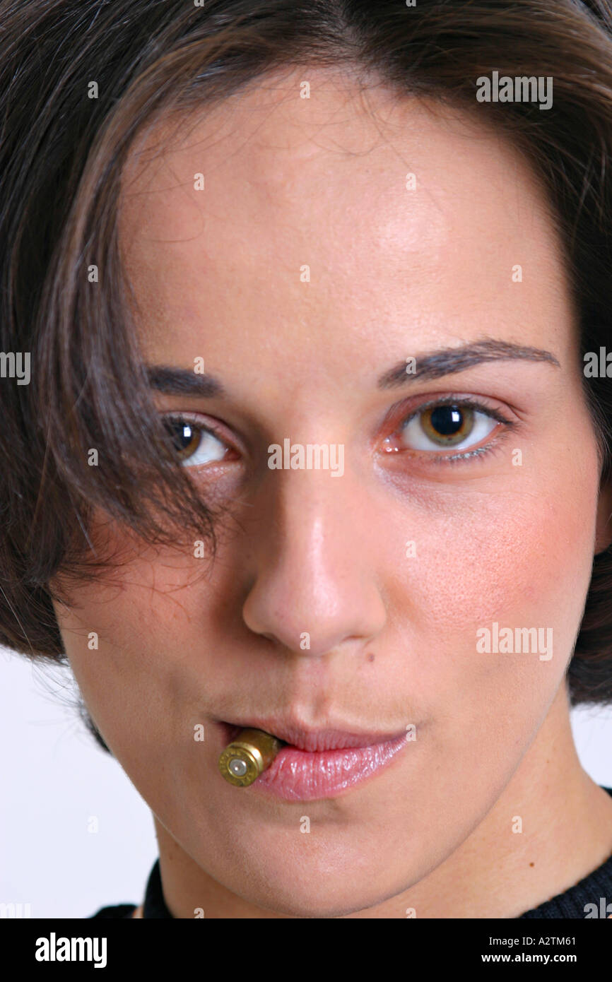 Junges Model mit einer Kugel Patrone zwischen die Lippen trotzig in die Kamera schaut Stockfoto