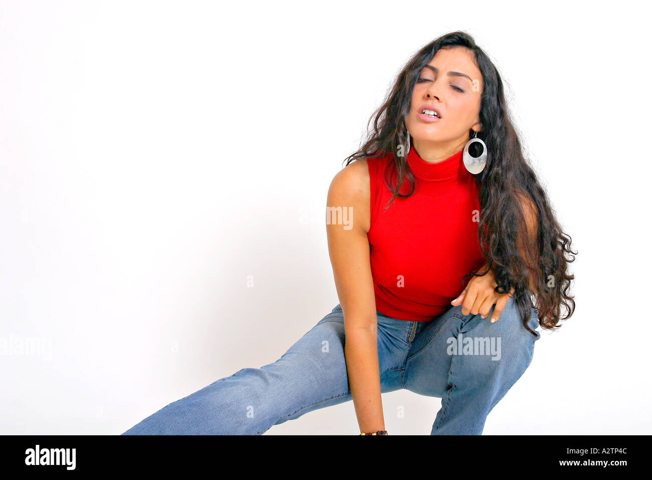 Mittlere Aufnahme von spanisches Mädchen mit roten Top und Jeans mit hocken verlängert Bein und schloss die Augen Stockfoto