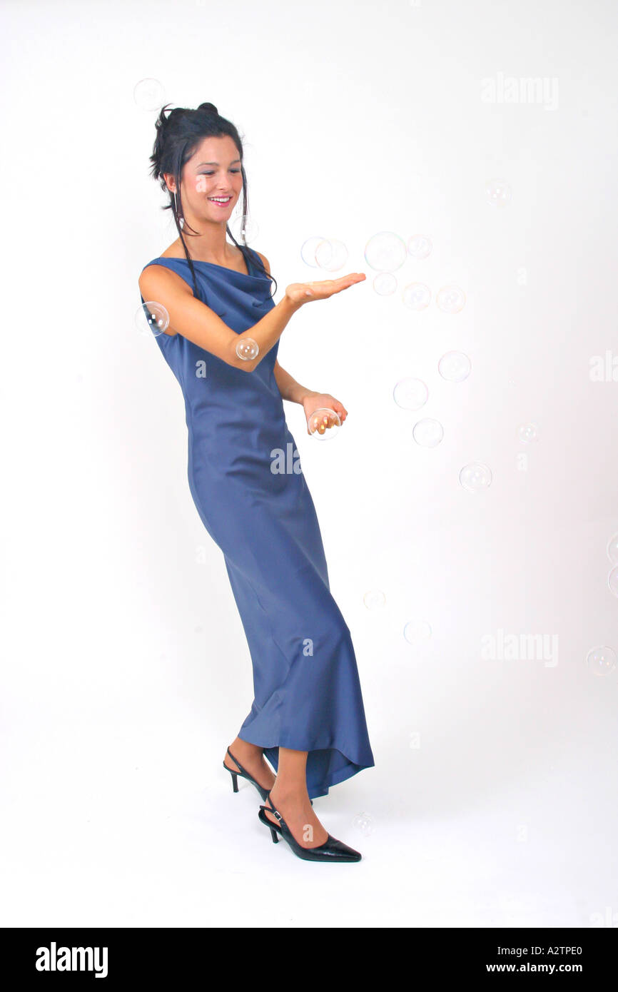 F.s. junge Frau in einem blauen Abendkleid mit Seifenblasen mit der Hand spielen verlängert Palm-up Stockfoto