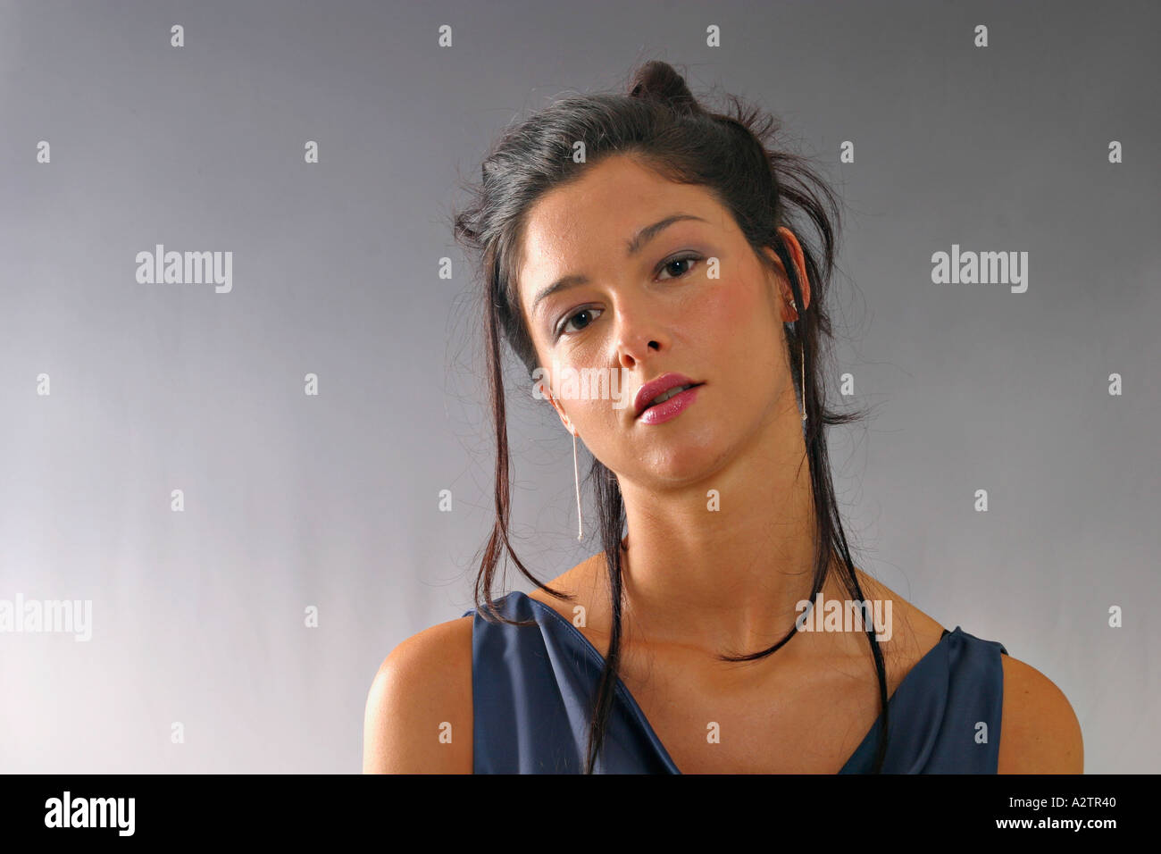 Bezugseinheiten dramatische Beleuchtung der junge Frau in blauen formelle Gewand sehnsüchtig in die Kamera schaut Stockfoto